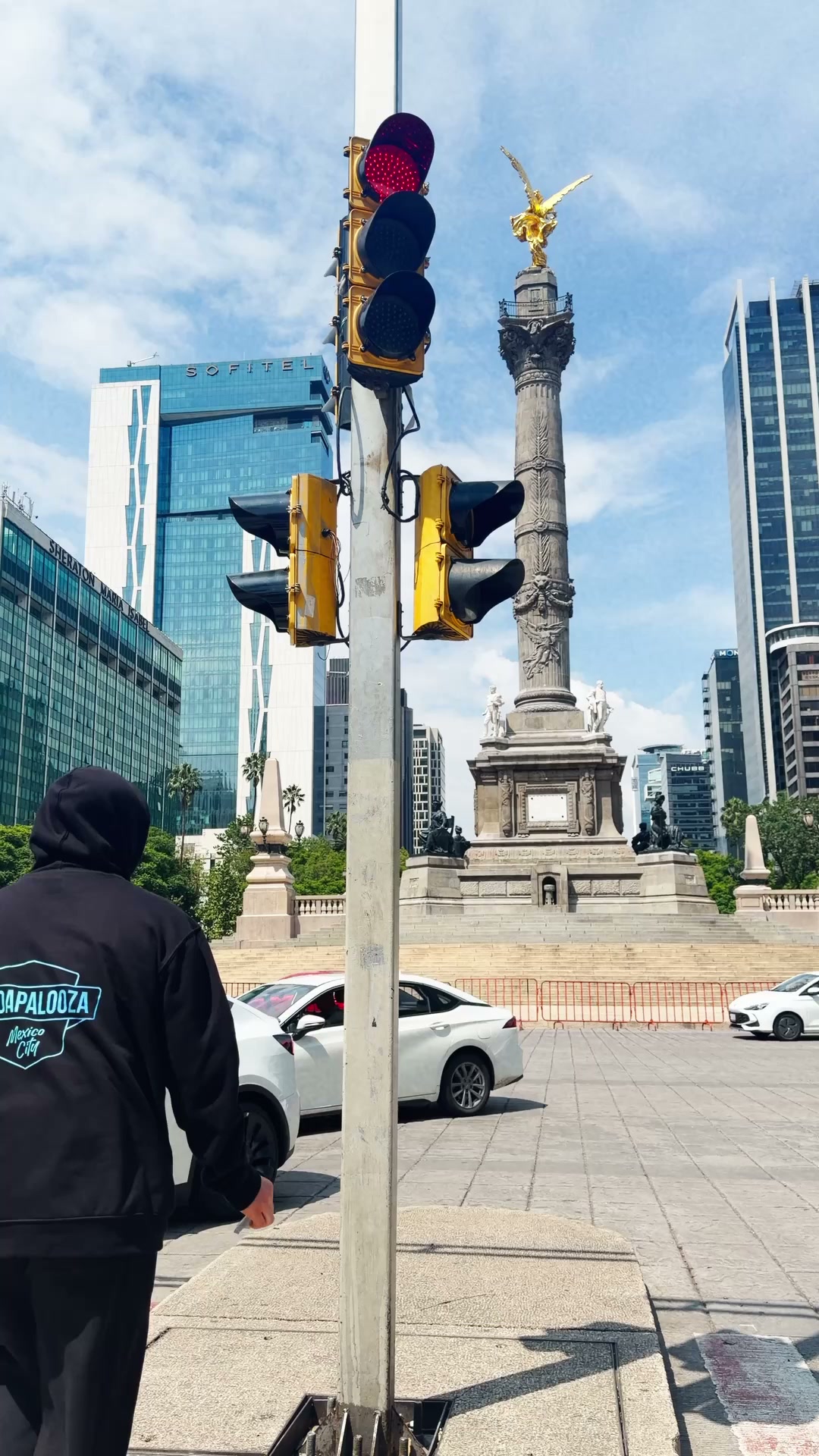 Hooded figure approaching a streetlight to place a sticker